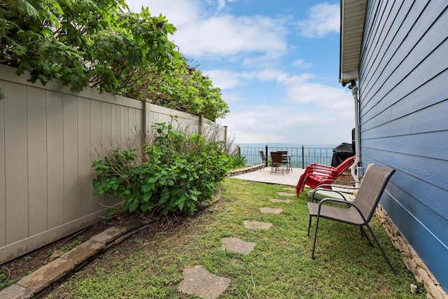 view of yard with a patio area, a fenced backyard, and a water view