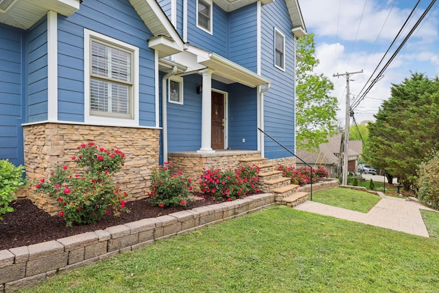 entrance to property featuring stone siding and a yard
