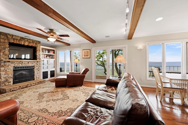 living area featuring beamed ceiling, baseboards, wood finished floors, and a fireplace