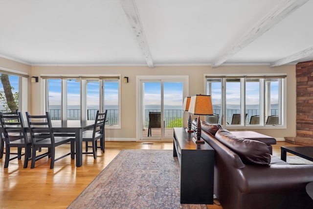 living area featuring beamed ceiling, baseboards, a water view, and light wood-type flooring