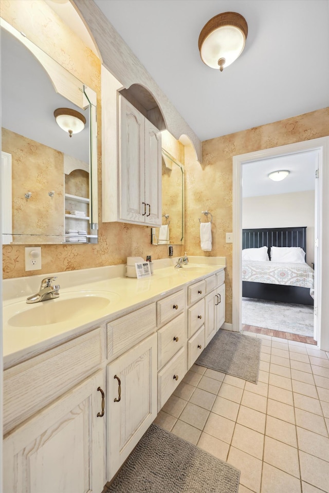 full bath featuring double vanity, tile patterned flooring, ensuite bathroom, and a sink