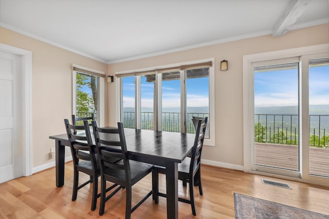 dining area with a water view, baseboards, visible vents, light wood-style floors, and ornamental molding