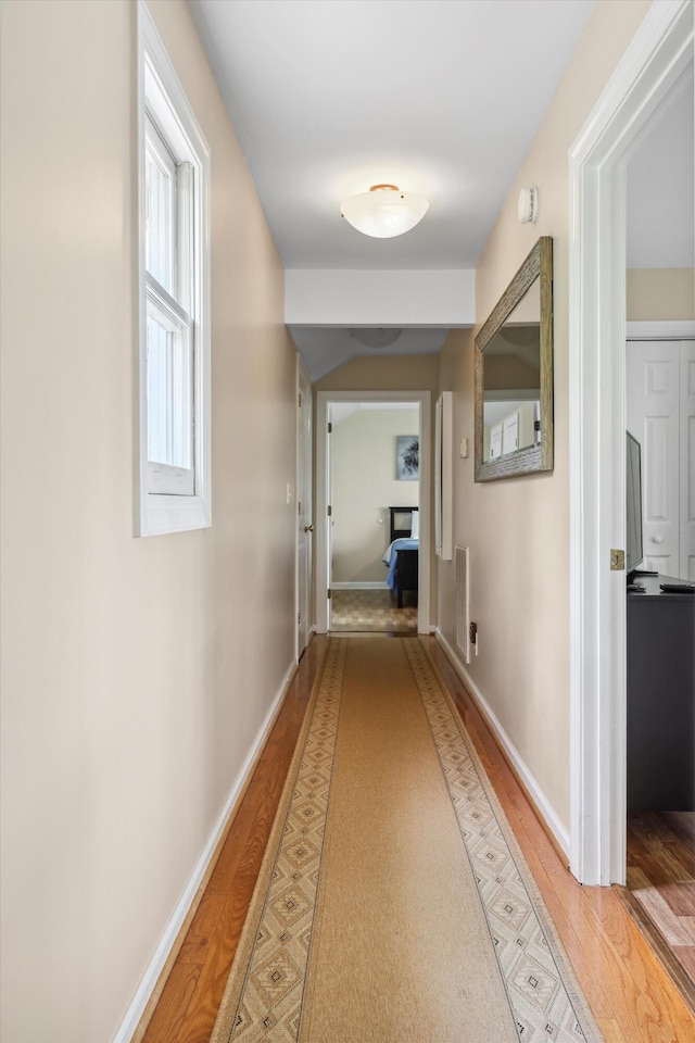 hall featuring baseboards and light wood-type flooring