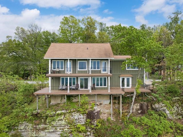 back of property with board and batten siding, roof with shingles, and a balcony