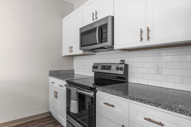 kitchen with stainless steel appliances, dark stone countertops, and white cabinetry