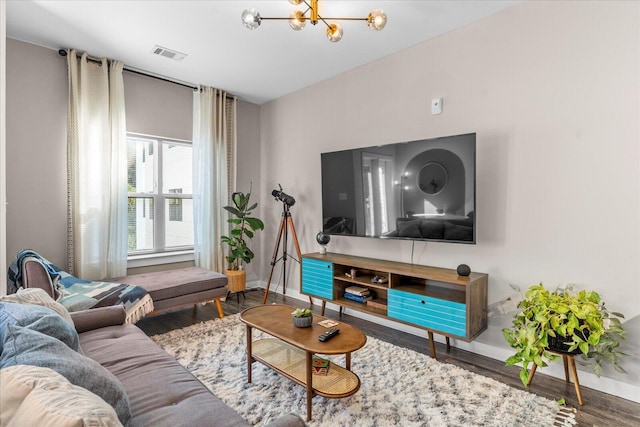 living area with visible vents, baseboards, wood finished floors, and a chandelier