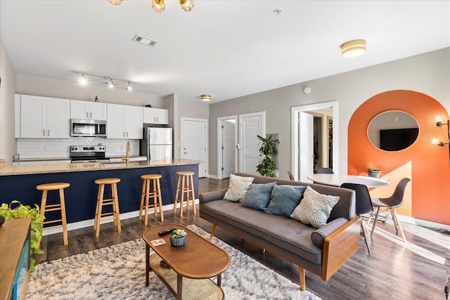 living area featuring baseboards, visible vents, and dark wood finished floors