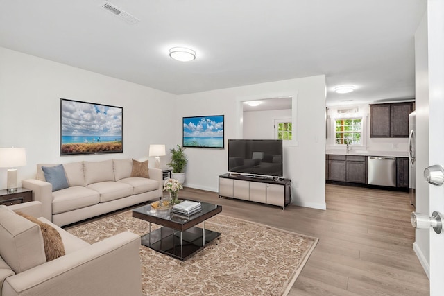 living room featuring light wood finished floors, visible vents, and baseboards