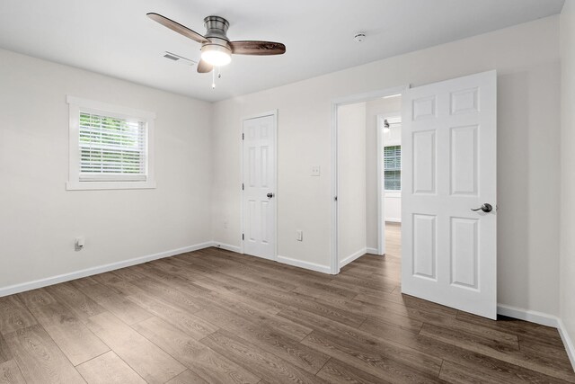 unfurnished bedroom with baseboards, dark wood-style flooring, visible vents, and a ceiling fan