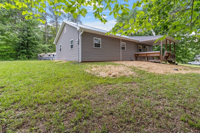 rear view of property featuring a lawn, metal roof, and a wooden deck