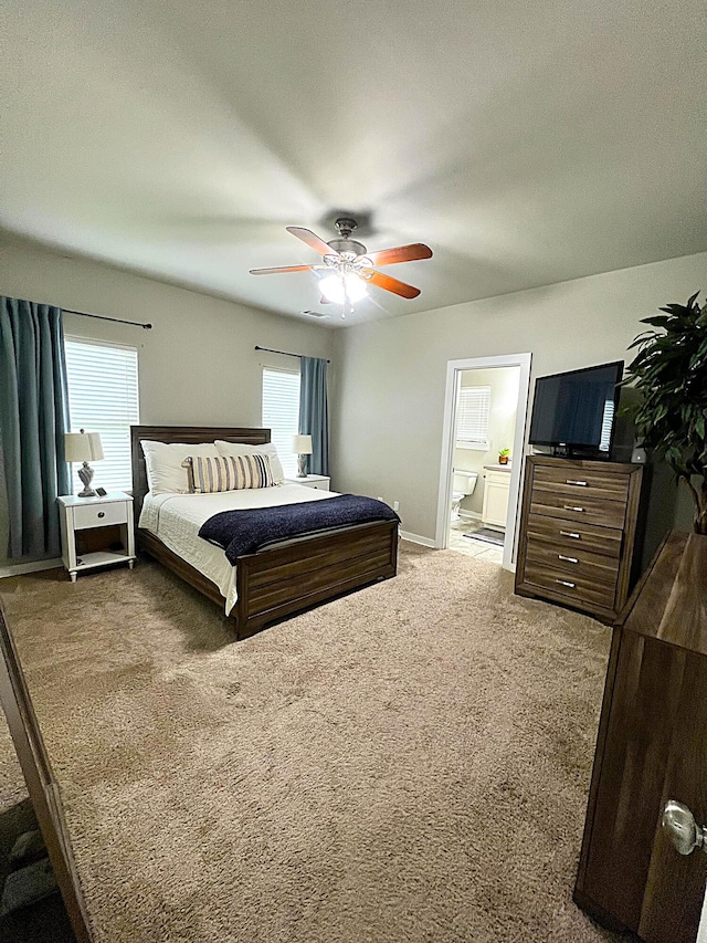 bedroom featuring carpet floors, a ceiling fan, ensuite bathroom, and multiple windows