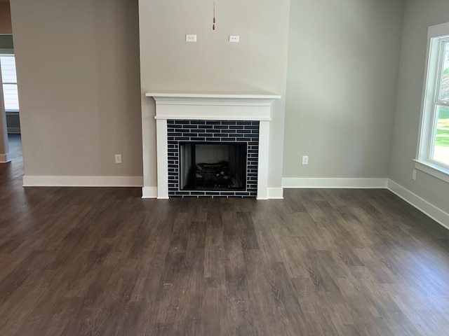unfurnished living room featuring a tile fireplace, baseboards, and dark wood-style flooring