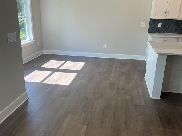 unfurnished dining area with baseboards and dark wood finished floors