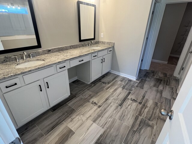 bathroom featuring baseboards, a sink, and double vanity