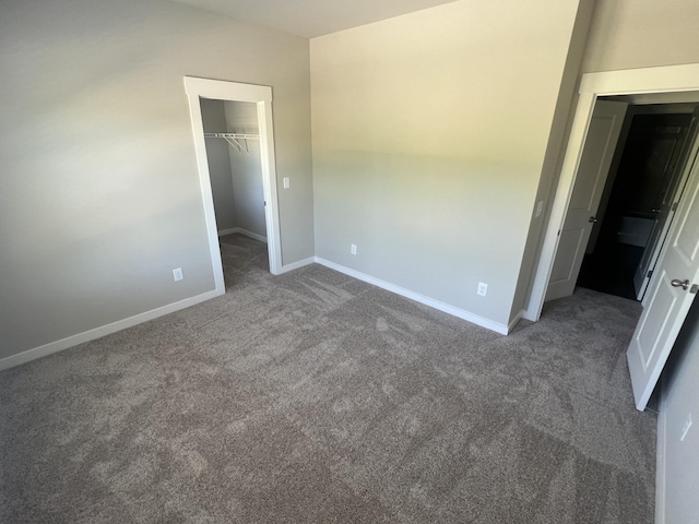 unfurnished bedroom featuring a closet, a spacious closet, carpet flooring, and baseboards