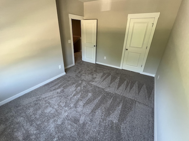 unfurnished bedroom featuring dark carpet and baseboards