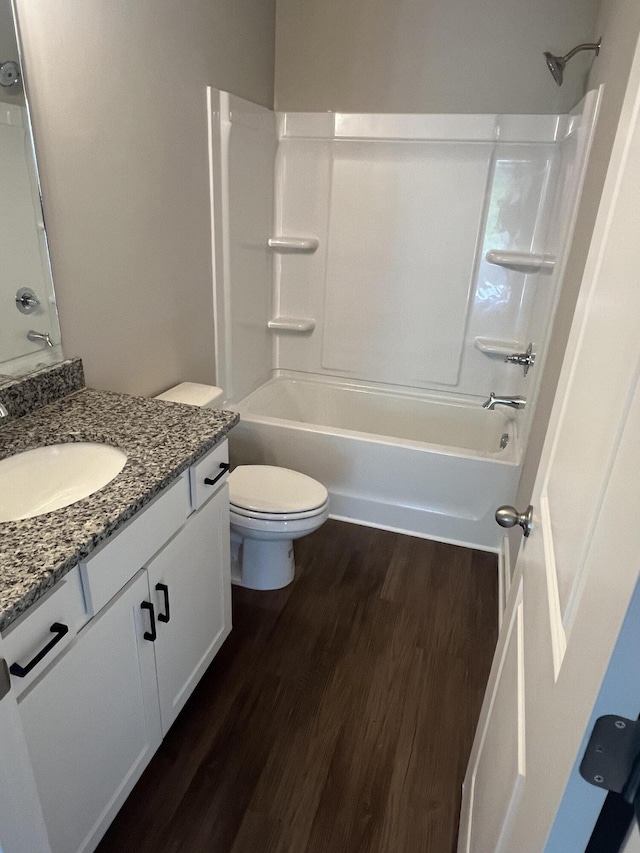 full bath featuring toilet, vanity, wood finished floors, and tub / shower combination