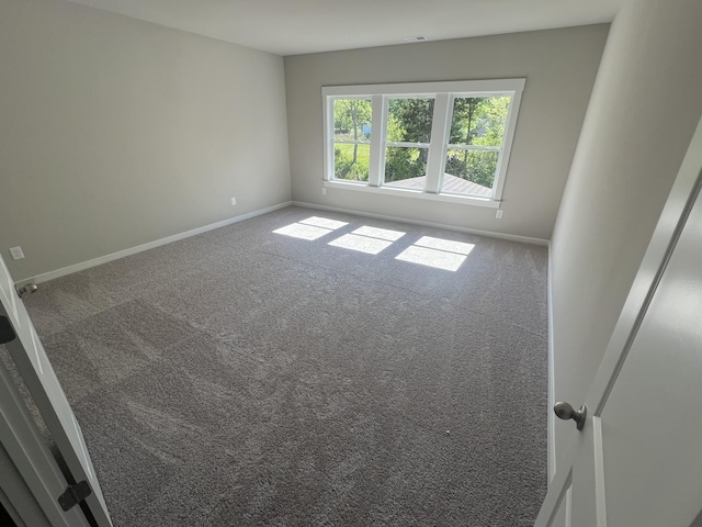 unfurnished room with carpet flooring and baseboards