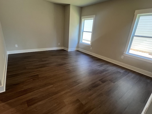 empty room featuring dark wood finished floors and baseboards
