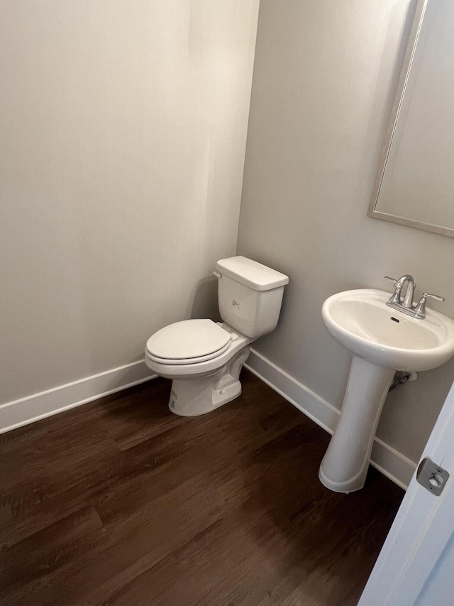 half bath with wood finished floors, toilet, and baseboards