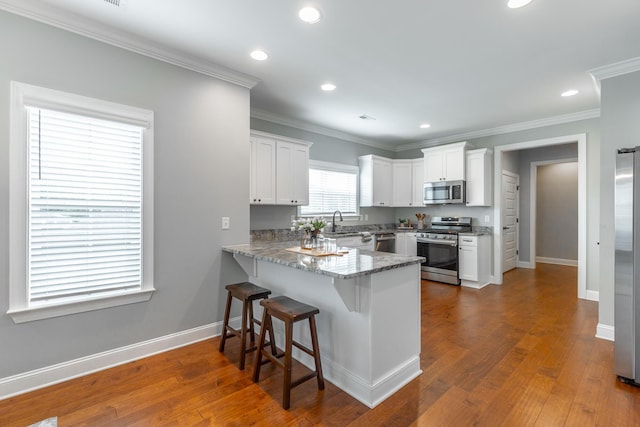 3495 Travertine Ln, Chattanooga, TN 37405 - kitchen featuring a kitchen breakfast bar, a peninsula, baseboards, white cabinets, and appliances with stainless steel finishes