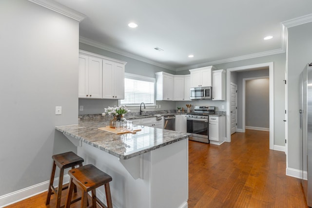 3495 Travertine Ln, Chattanooga, TN 37405 - kitchen featuring white cabinetry, a breakfast bar area, appliances with stainless steel finishes, dark wood finished floors, and a peninsula