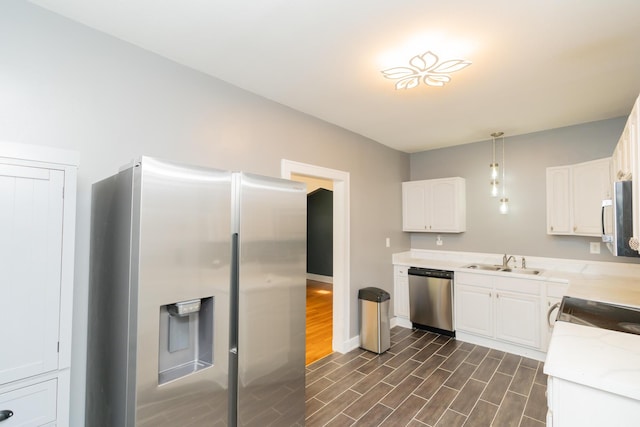 kitchen with white cabinets, dark wood finished floors, light countertops, a sink, and appliances with stainless steel finishes