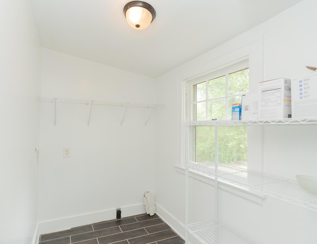 clothes washing area featuring baseboards and dark wood-style flooring