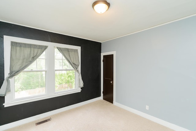 empty room featuring baseboards, visible vents, carpet, and ornamental molding