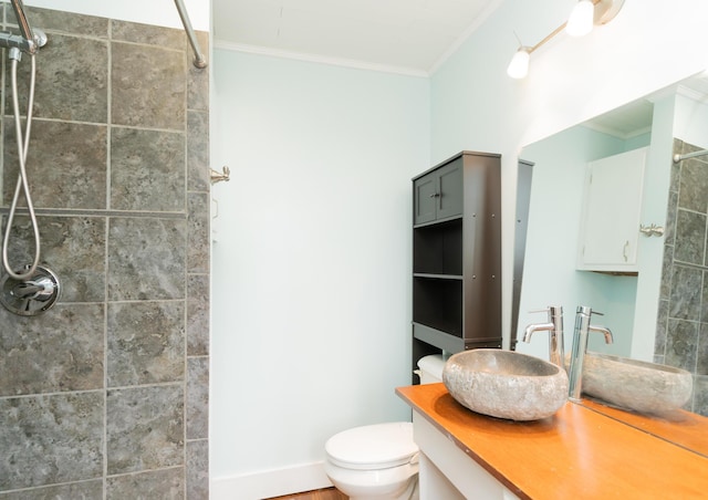 full bath featuring vanity, crown molding, tiled shower, and toilet