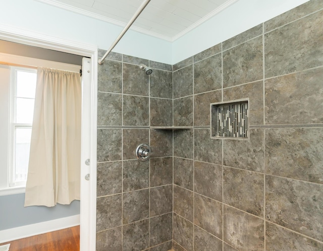 bathroom featuring crown molding, wood finished floors, baseboards, and a tile shower