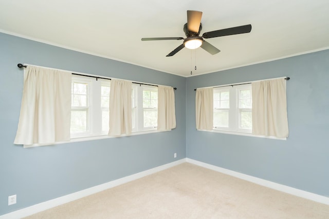 carpeted empty room with baseboards, ceiling fan, and crown molding
