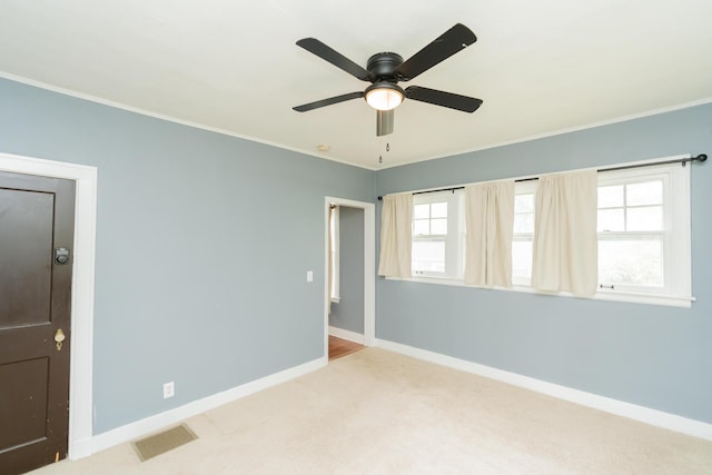 unfurnished room with visible vents, crown molding, baseboards, and light carpet