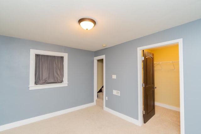 unfurnished bedroom featuring baseboards, carpet, a closet, and a walk in closet