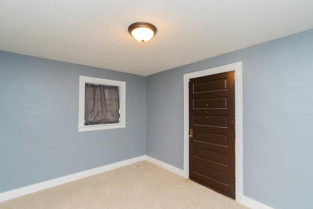 empty room featuring baseboards and light carpet