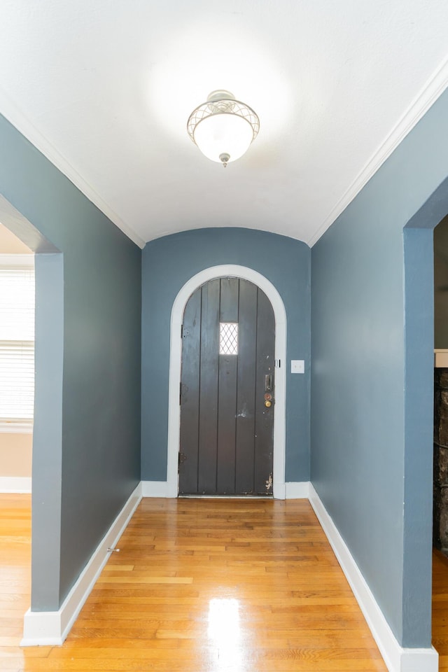 foyer entrance featuring wood finished floors, crown molding, and baseboards