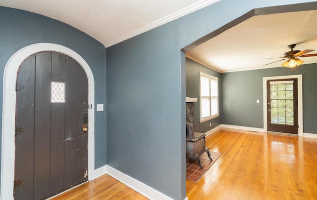entryway with arched walkways, baseboards, ornamental molding, and wood finished floors