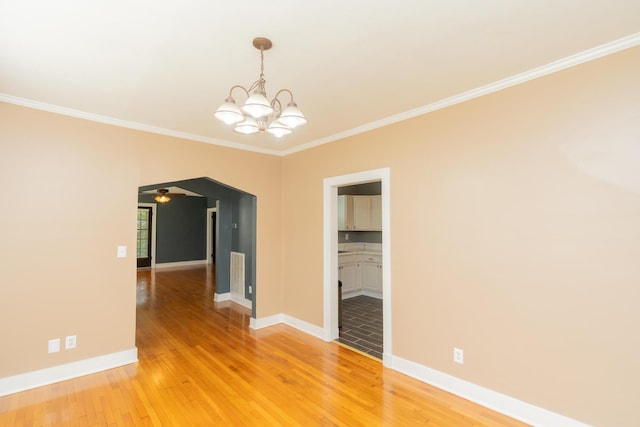 spare room featuring baseboards, ornamental molding, ceiling fan with notable chandelier, and light wood-style flooring