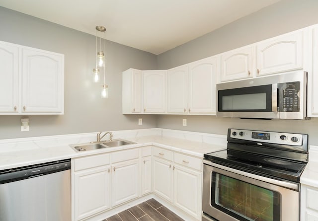 kitchen featuring white cabinets, appliances with stainless steel finishes, dark wood-type flooring, and a sink