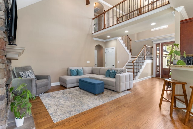 8209 Robertsview Dr, Ooltewah, TN 37363 - living room featuring a stone fireplace, arched walkways, stairs, a towering ceiling, and baseboards