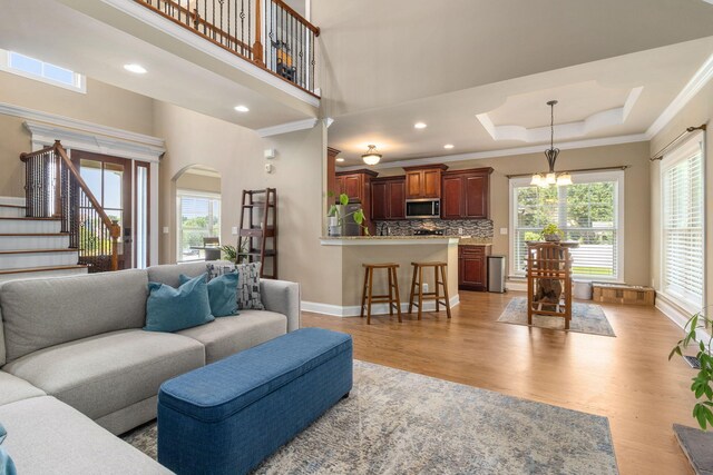 8209 Robertsview Dr, Ooltewah, TN 37363 - living room with healthy amount of natural light, light wood finished floors, ornamental molding, stairs, and arched walkways