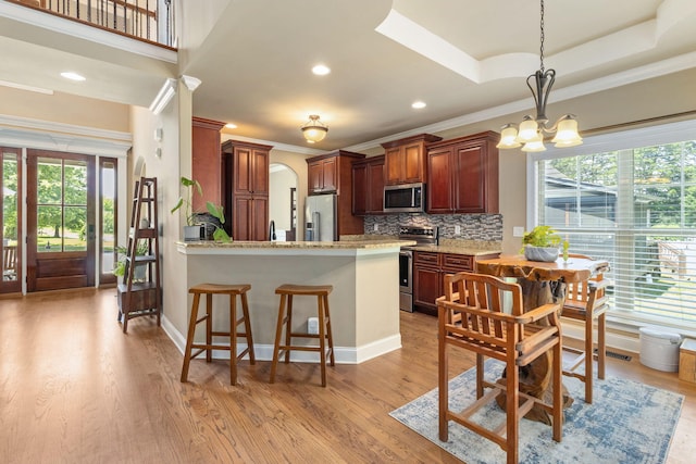 8209 Robertsview Dr, Ooltewah, TN 37363 - kitchen with stainless steel appliances, ornamental molding, a chandelier, backsplash, and a peninsula
