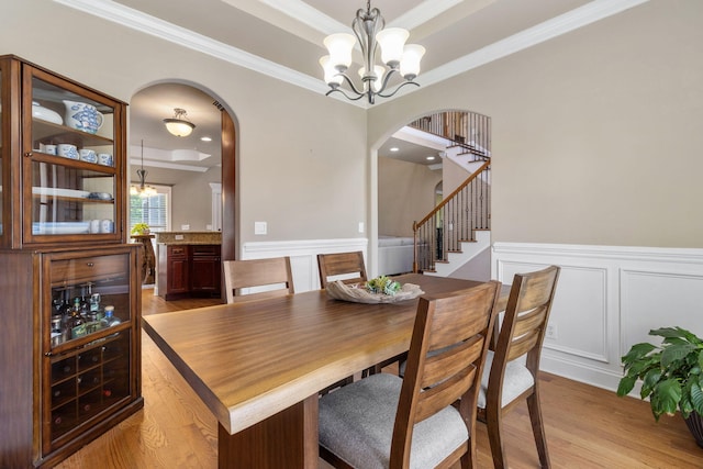 8209 Robertsview Dr, Ooltewah, TN 37363 - dining area with arched walkways, a raised ceiling, a chandelier, a decorative wall, and ornamental molding