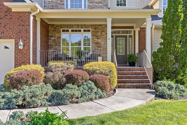 view of exterior entry featuring a garage, covered porch, and stone siding
