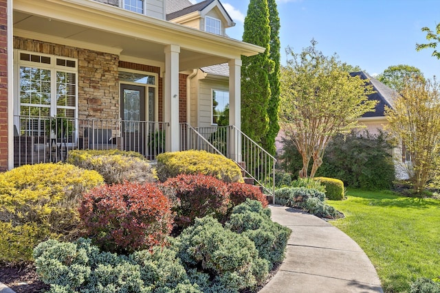 property entrance featuring a yard, stone siding, and covered porch