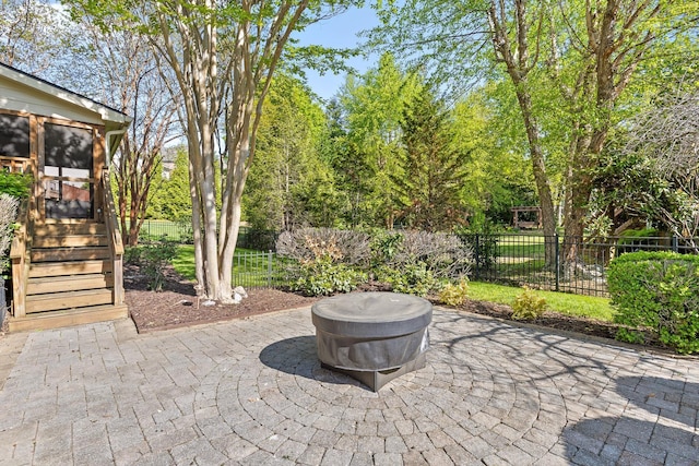 view of patio / terrace featuring fence, a sunroom, and a fire pit