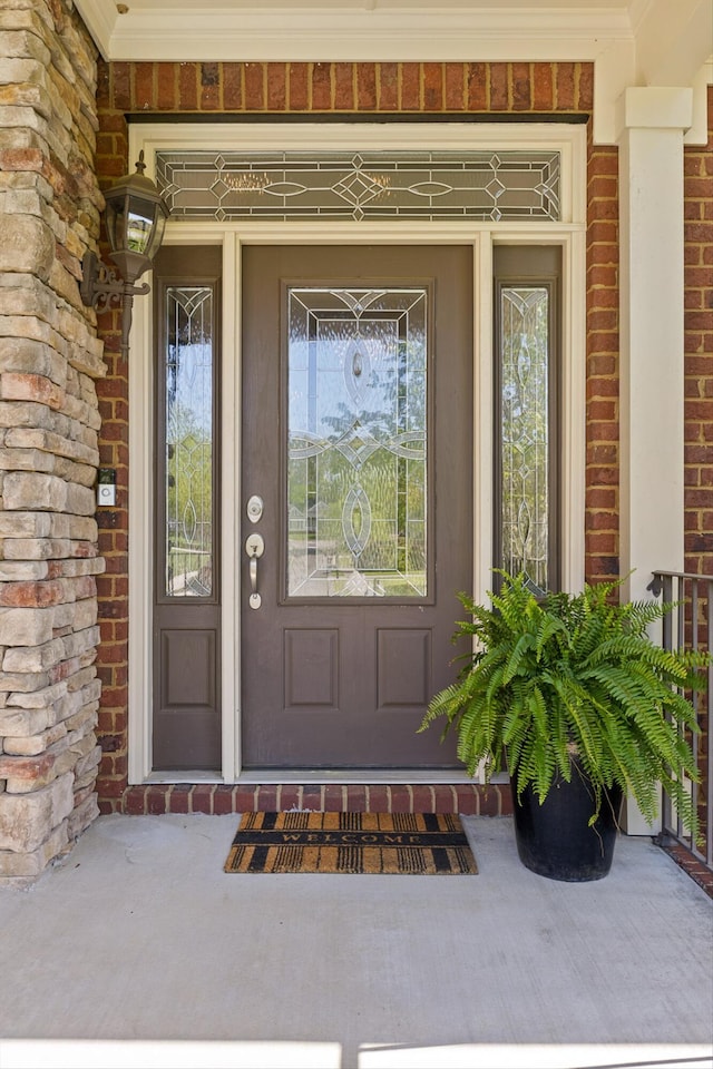 view of exterior entry with covered porch and brick siding