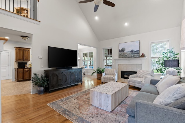 living area with a fireplace, ceiling fan, high vaulted ceiling, recessed lighting, and light wood-style flooring