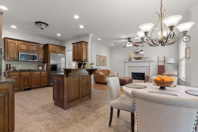 kitchen featuring a breakfast bar, ceiling fan with notable chandelier, stainless steel appliances, open floor plan, and a peninsula