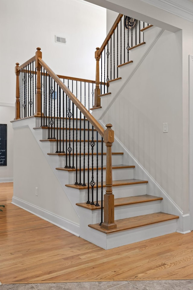 staircase with baseboards, visible vents, and wood finished floors